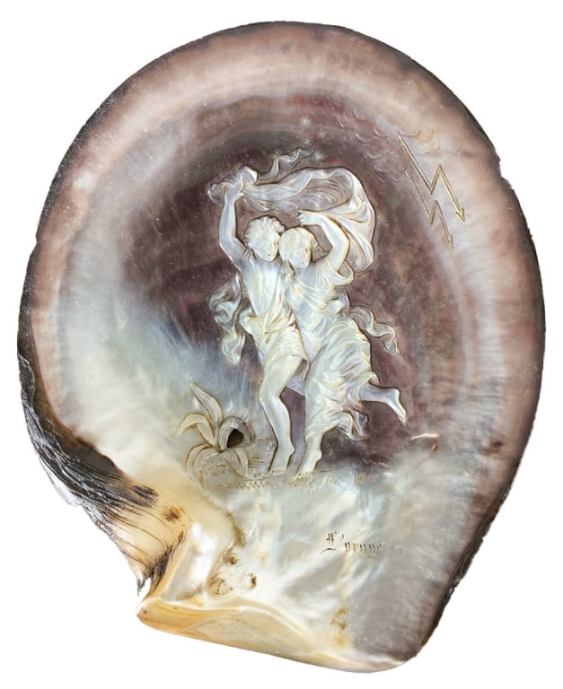 Paul & Virginie Carved Mother of Pearl Shell: Carved mother-of-pearl shell depicting Paul and Virginie fleeing a storm, with detailed drapery, engraved lightning, and the inscription 'L'Orage.' Iridescent surface with fine relief work.Dimensions: