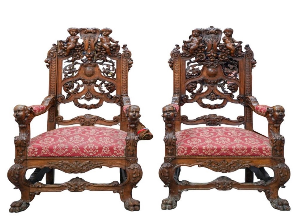 Pair of Renaissance Revival Carved Oak Armchairs: Pair of Renaissance Revival carved oak armchairs with cherub and foliate motifs, scroll arms, cabriole legs, and red-gold damask upholstery. Each piece measures approximately 60 inches high by 26 inch