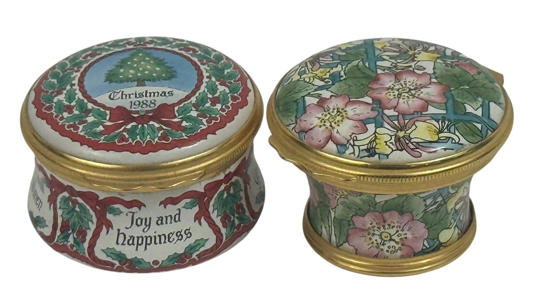 Pr of Halcyon Days Enamel Porcelain Trinket Boxes: Pair of Halcyon Days hand-enamel porcelain trinket boxes. Each miniature round box is finely hand-painted and fitted with gilt metal mounts. One celebrates Christmas 1988, decorated with holly wreaths