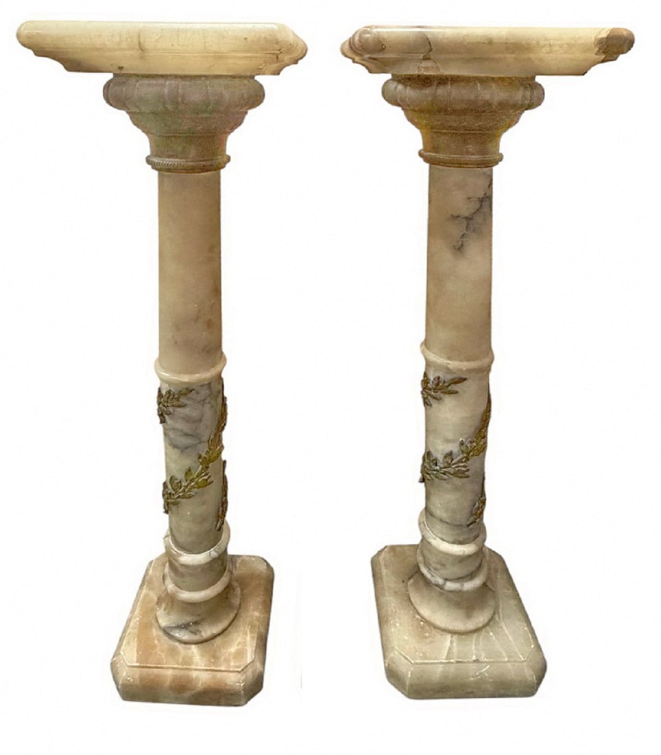 Pair of Antique Alabaster & Bronze Pedestals: Tall carved alabaster pedestals with bronze mounts, featuring beveled tops, bronzed capitals, tapered shafts with bronze garlands, and stepped octagonal bases.Each piece measures approximately 41.5 in