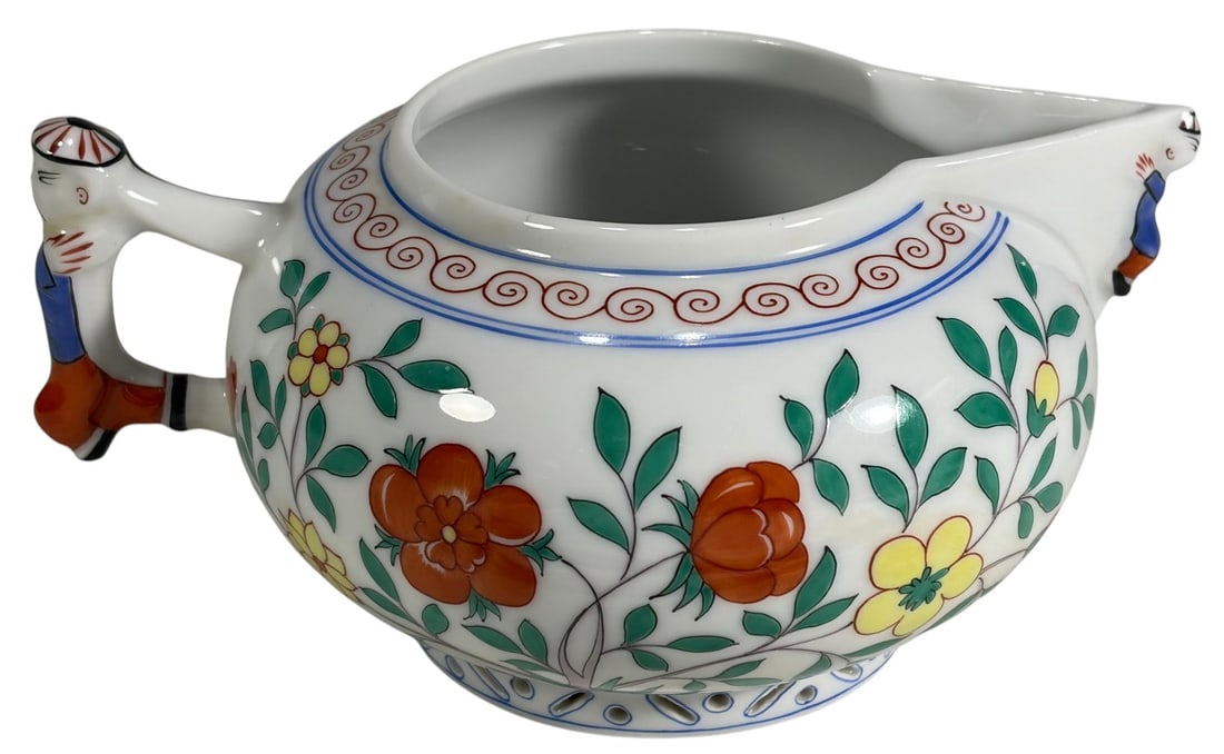 Herend Hungarian Oriental Porcelain Creamer: Herend Hungary porcelain creamer, hand-painted in the Oriental Motif pattern with vibrant floral designs and figural handle and spout depicting oriental figures. The underside bears the blue Herend Hu
