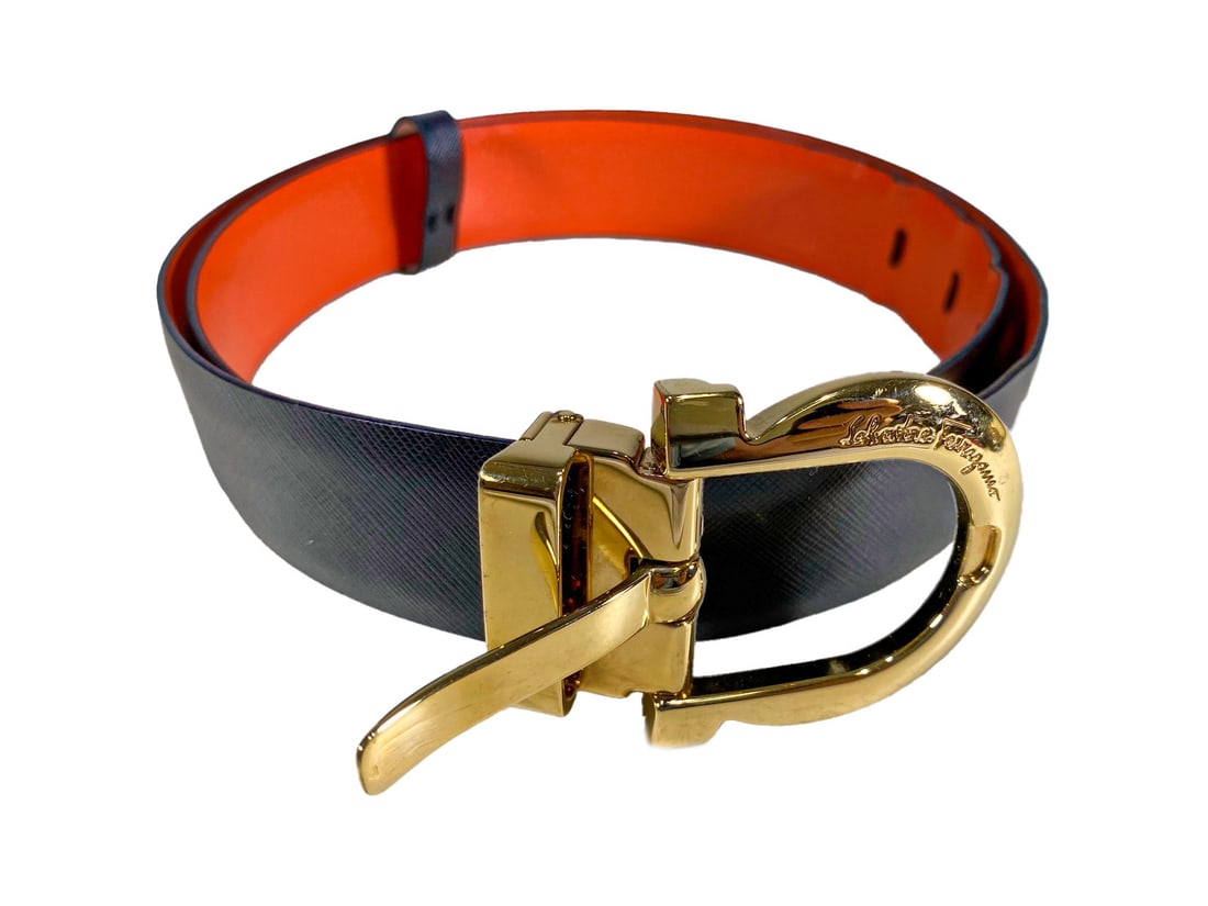 Salvatore Ferragamo Black & Orange Leather Belt: Stylish Ferragamo belt crafted in black cross-grain and smooth orange leather, featuring a signature gold-tone Gancini buckle. Buckle is engraved with 'Salvatore Ferragamo.' The belt measures approxim