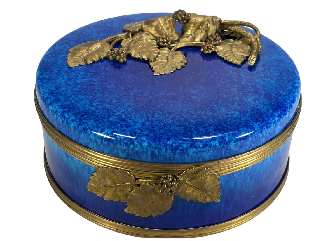 Antique French Sevres Bronze Flambe Porcelain Box: Antique French Sevres porcelain box with blue flambe glaze and gilt bronze grapevine mounts. Round form with a hinged lid. Marked 'Sevres' and retains its retail paper label to its base.Dimensions: 3.