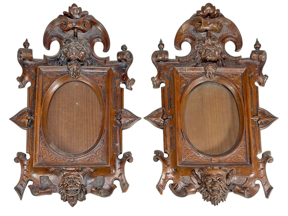 Pair of German Black Forest Wood Picture Frames: German pair of carved Black Forest wood picture frames with foliate scrolls and grotesque mask motifs. Oval openings with deep relief carving and dark stained finish. Each piece measures approximately