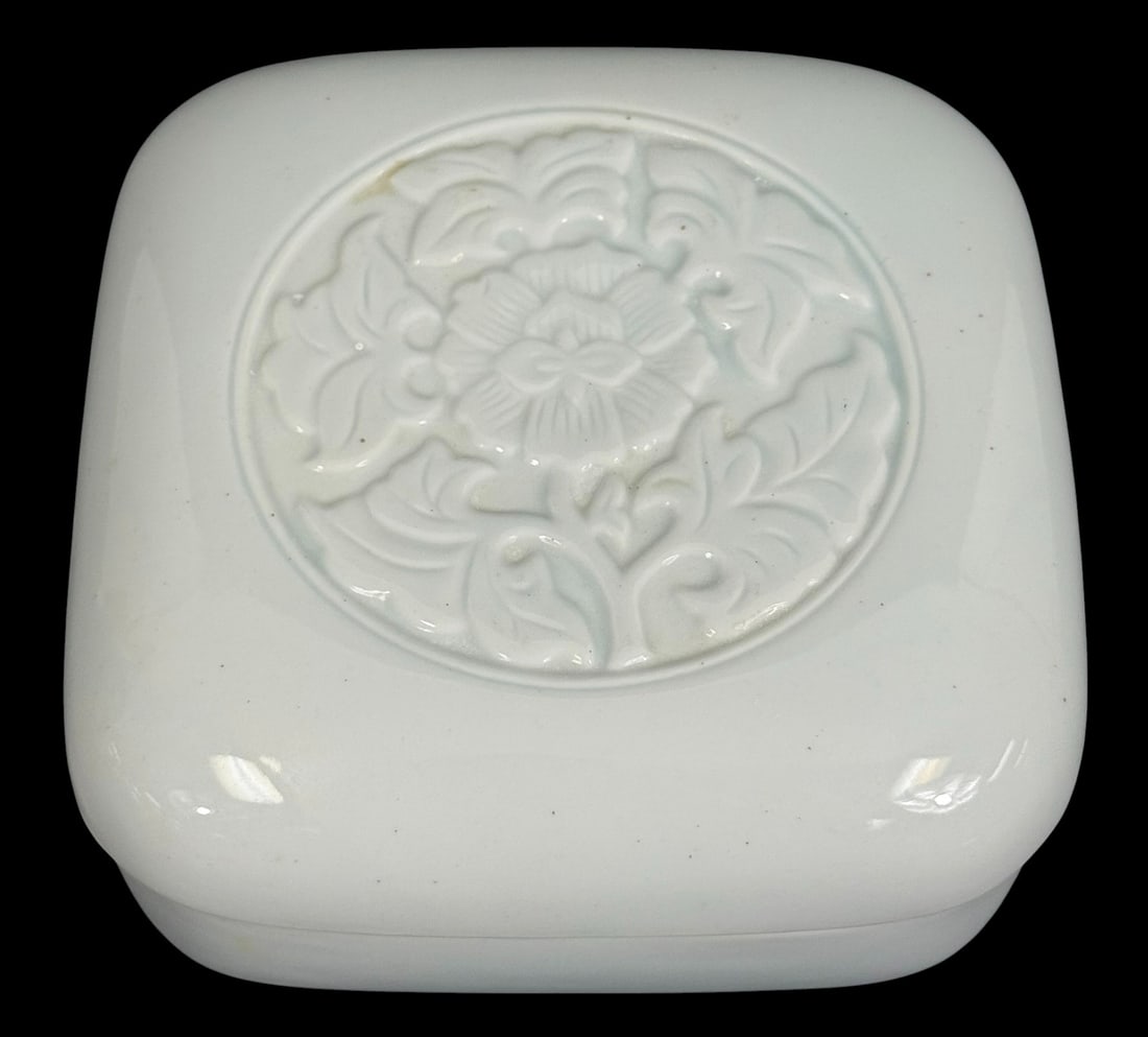 Tiffany & Co. 1979 Porcelain Lidded Trinket Box: Tiffany & Co. porcelain lidded box featuring a square form with rounded edges and a soft celadon glaze, with a raised floral medallion motif centered on the lid. The delicate relief pattern evokes cla