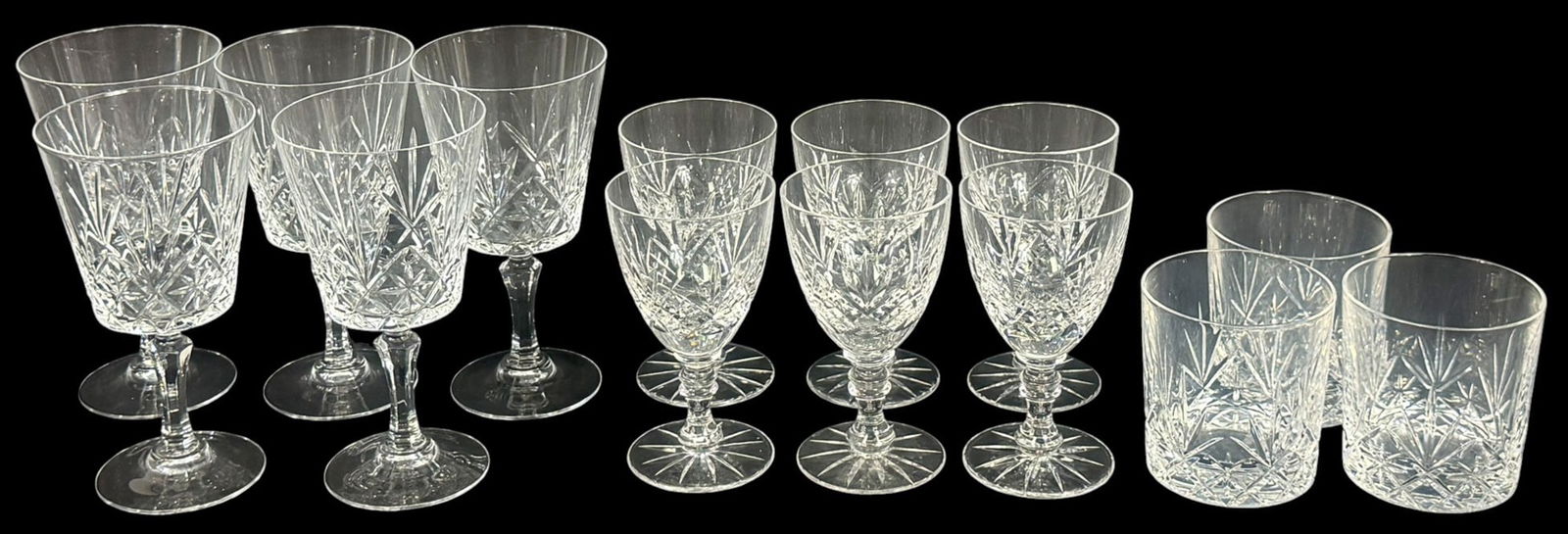 Crystal Glasses in the Style of Waterford 14pc LOT: Lot of fourteen cut crystal glasses is crafted in a classic style reminiscent of Waterford. This group includes (5) tall wine glasses, (6) goblets, and (3) lowball tumblers. Unsigned. The tallest glas