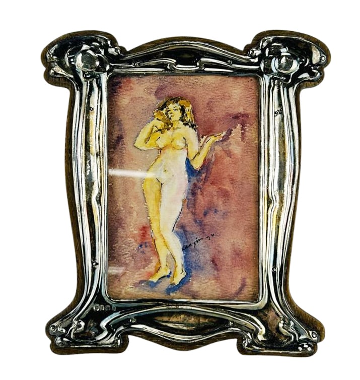 Sterling Mounted Nude Watercolor Framed Painting: Figure study of a female standing nude watercolor painting on paper. Mounted in a wood frame with an Art Nouveau style English silver surround. Presented under glass. Easel stand. Signed lower right.
