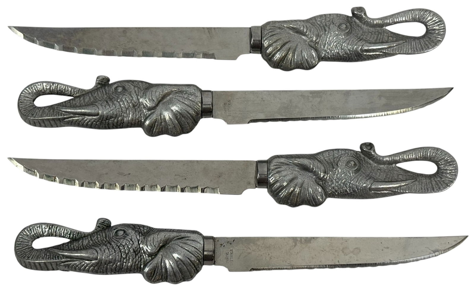 Arthur Court Aluminum Elephant Steak Knives 4pcs: Lot of four vintage Arthur Court steak knives featuring sculpted elephant head handles cast in aluminum. Each knife showcases finely detailed textures, with the elephant?s trunk forming a curved loop