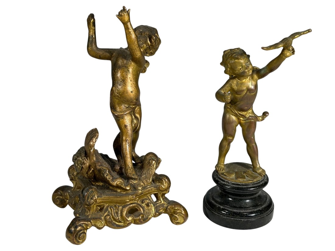 Antique Cherubs Gilt Bronze Sculptures 2pc LOT: Pair of antique gilt bronze cherub sculptures, one releasing a bird on a round plinth base with black marble finish, and one with raised arms on an ornate Rococo-style footed base. The largest measure