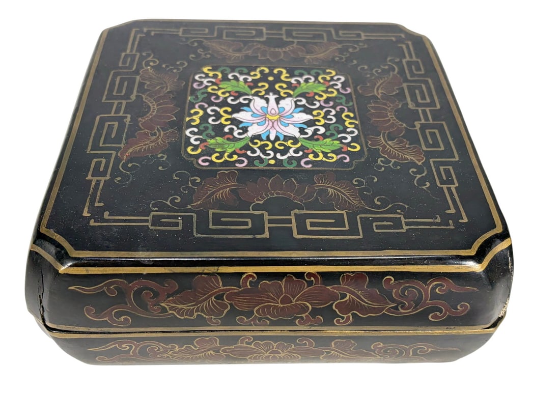 Chinese Cloisonne & Lacquer Wood Box Enamel: Black lacquered wood box with lift-off lid, decorated with gilt floral scrollwork and a cloisonne-style enamel floral panel on the top.Dimensions: 3 X 8 X 8 in. Condition: Good overall condition