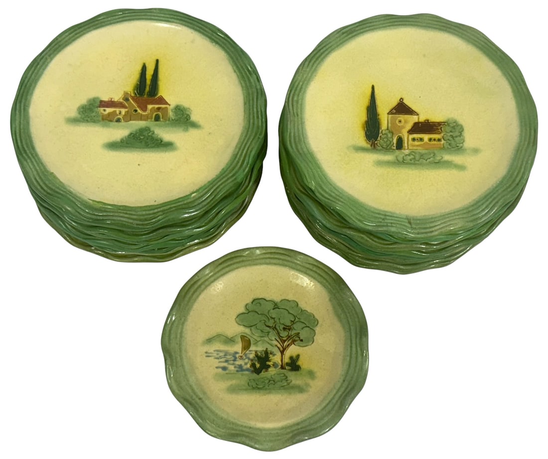 Vallauris French Pastoral Pottery Plates 18pc SET: Set of eighteen Vallauris French hand-painted ceramic plates, featuring charming pastoral scenes with cottages, trees, and landscapes. The plates have a rustic cream glaze with crackle finish and gree