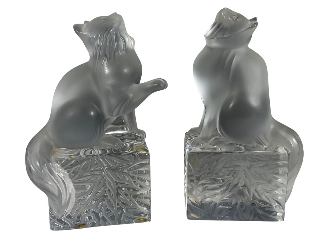 Lalique Frosted Crystal Cat Paperweights 2pc LOT: Pair of Lalique frosted crystal cat paperweights, one standing with raised paw and one seated, each on a clear square base with etched leaf motif, signed 'Lalique Copyright France.' The largest