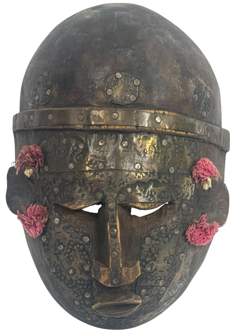 African Handcrafted Tribal-Style Wooden Mask: Handcrafted wooden mask in the style of traditional African tribal ceremonial art. The mask features a bold geometric facial structure with a dark patina and is richly overlaid with hammered and