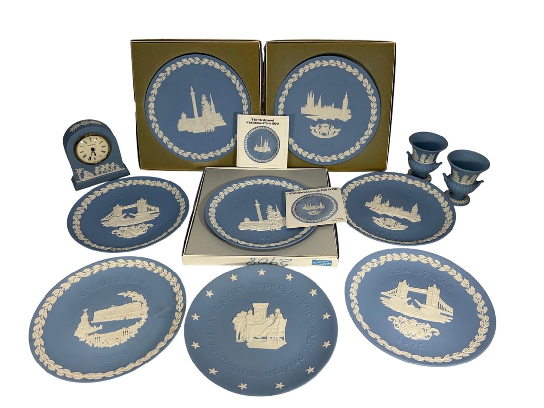 Wedgwood Jasperware Plates, Vase & Clock 11pc LOT: Wedgwood group of eleven blue jasperware pieces, including Christmas plates, a Bicentennial plate, a mantel clock, and two urn-form bud vases. All with applied white neoclassical relief decoration.