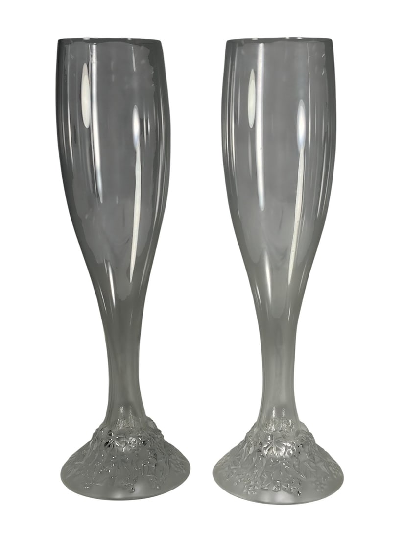 Lalique Celebration 2000 Champagne Flutes 2pc LOT: Pair of Lalique France Celebration 2000 champagne flutes with clear bowls and frosted bases molded with holly leaves and berries. Each acid etched 'Lalique France' and 'Lalique Celebration 2000' to it