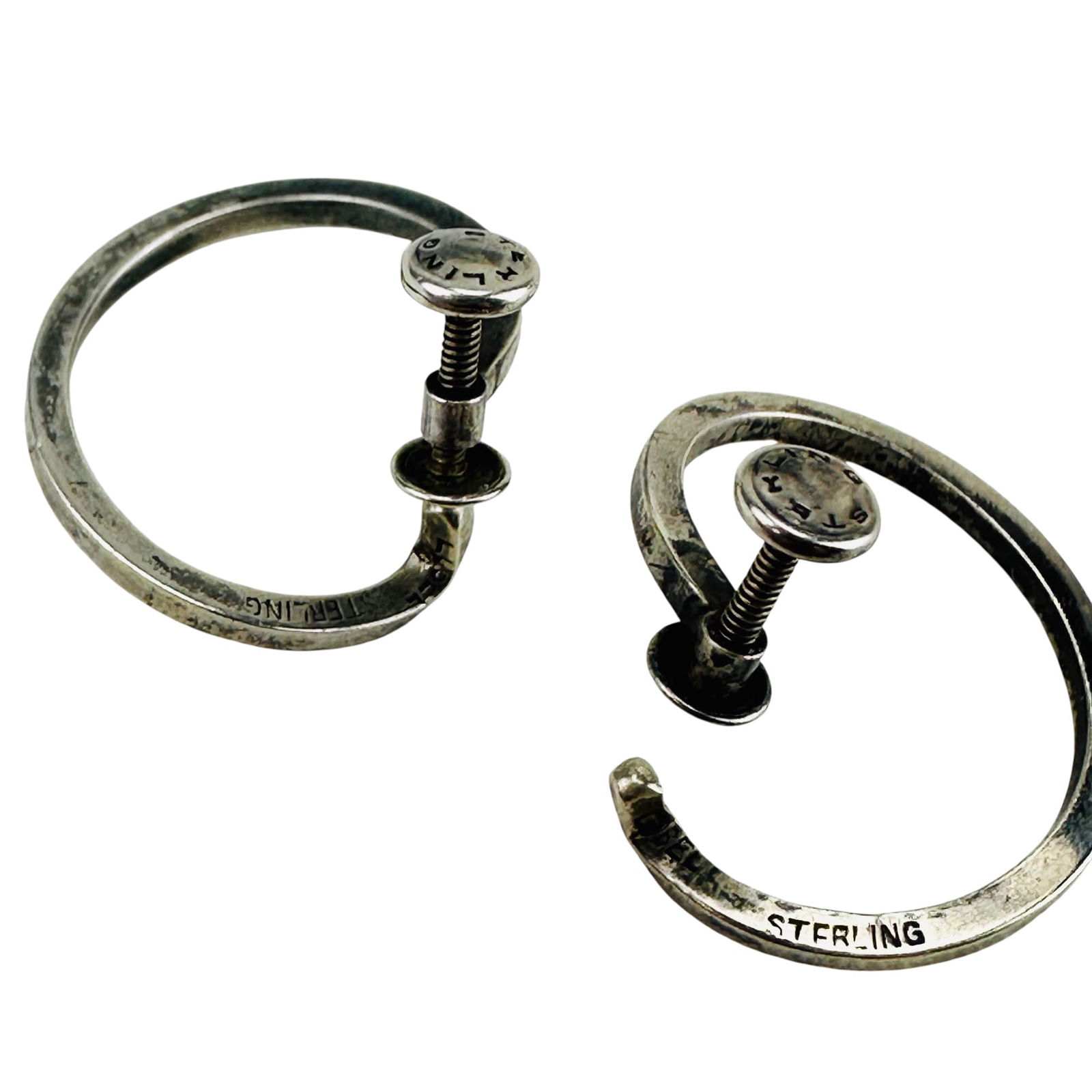 Paul Lobel Modernist Sterling Spiral Hoop Earrings: Paul Lobel (American,1889-1983), celebrated and renowned silversmith. Features a pair of asymmetrical spiral hoop earrings with screw-back fittings. Measure approximately .75" x .75". Marked Lobel Ste
