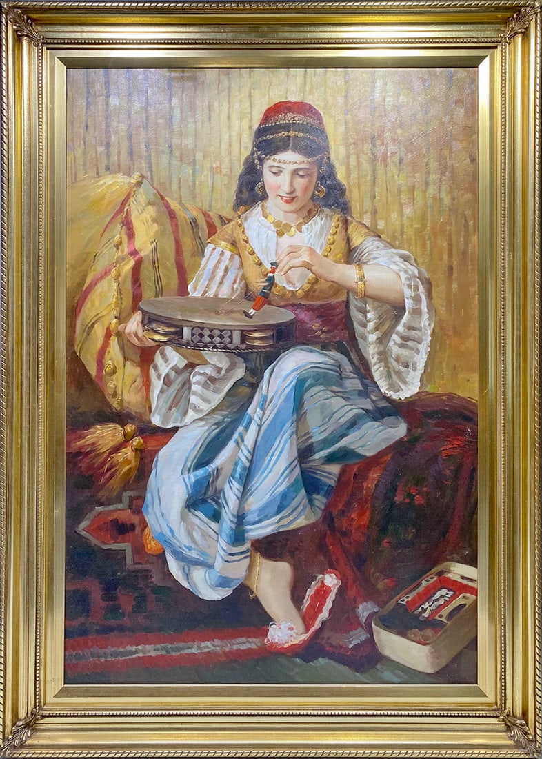 Orientalist Woman Playing Tambourine Oil on Canvas: Orientalist style oil painting on canvas depicting a seated woman in Middle Eastern or North African dress playing a tambourine with puppet figure. In ornate gold tone frame.Work Size: 36 x 24 in.Dime