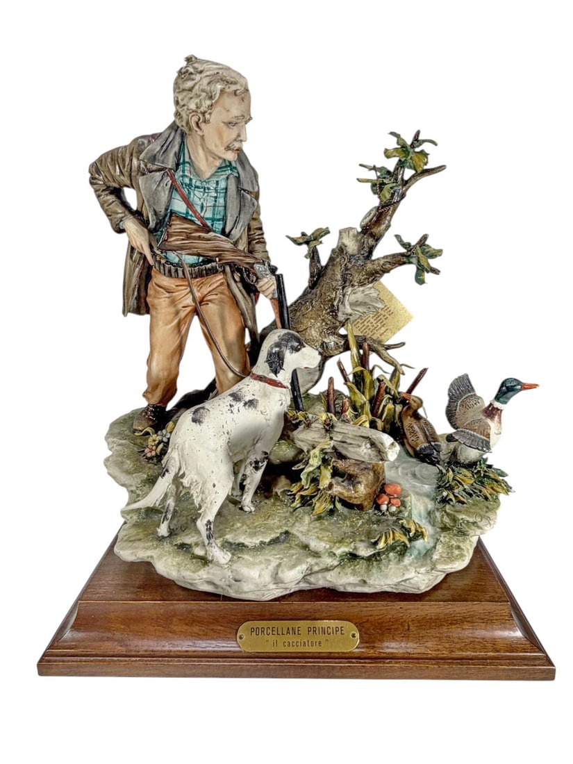 Capodimonte Porcellane Principe Il Cacciatore Fig: Capodimonte Porcellane Principe 'Il Cacciatore' porcelain figural group of a hunter with dog and game birds. Marked with crowned N, 'Porcellane Principe, Made in Italy,' on a wood plinth with brass