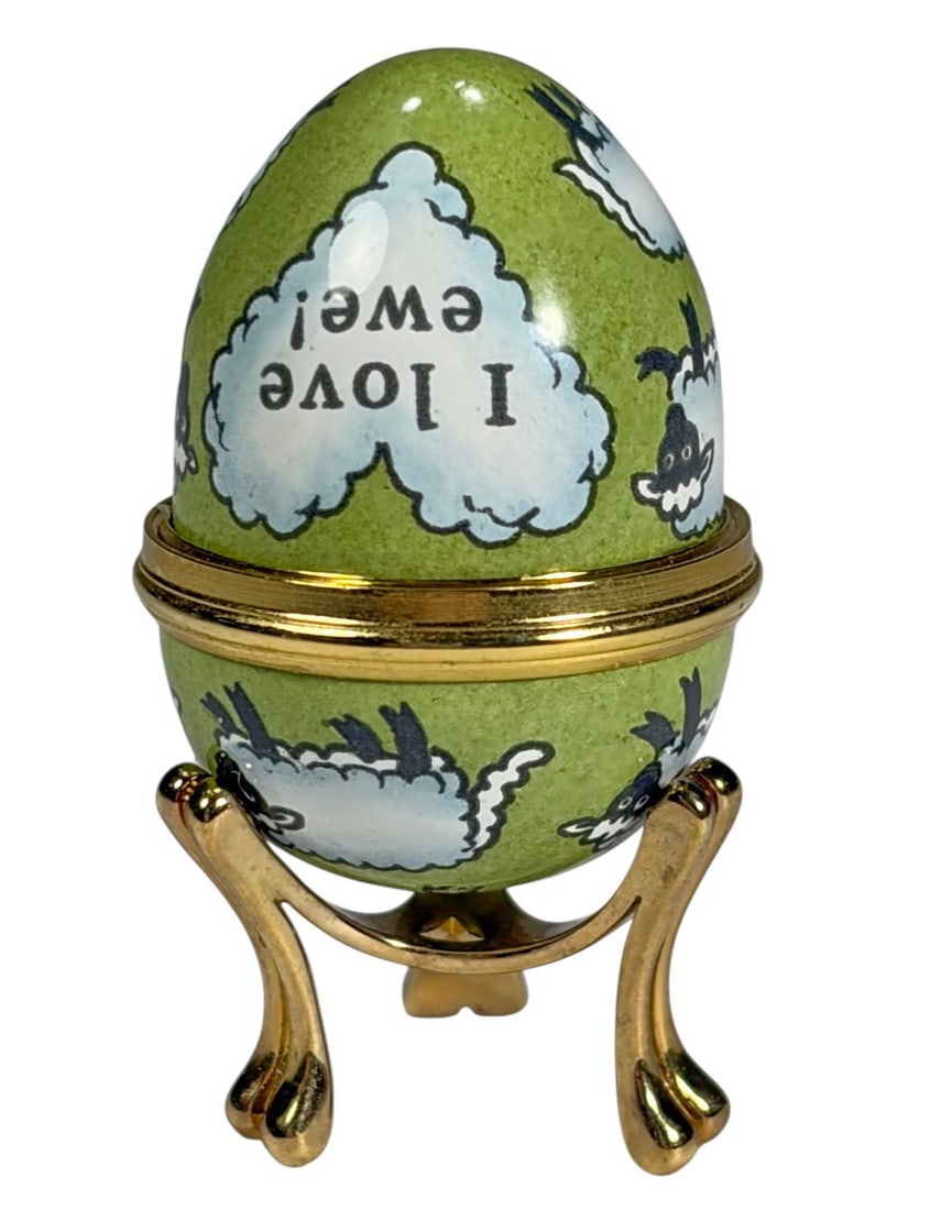 Halcyon Days England 'I love Ewe' Egg Trinket Box: Halcyon Days England I Love Ewe egg trinket box, handcrafted enamel. Green ground decorated with white sheep motifs around the body and a heart shaped cartouche inscribed I Love Ewe. Mounted with a gi