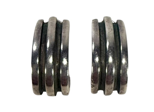 Tiffany & Co Atlas Groove Sterling Huggie Earrings: Pair of Tiffany & Co. sterling silver huggie hoop earrings from the Atlas Groove Collection. Featuring a triple-ribbed design with a softly contoured silhouette. These pierced earrings feature secure