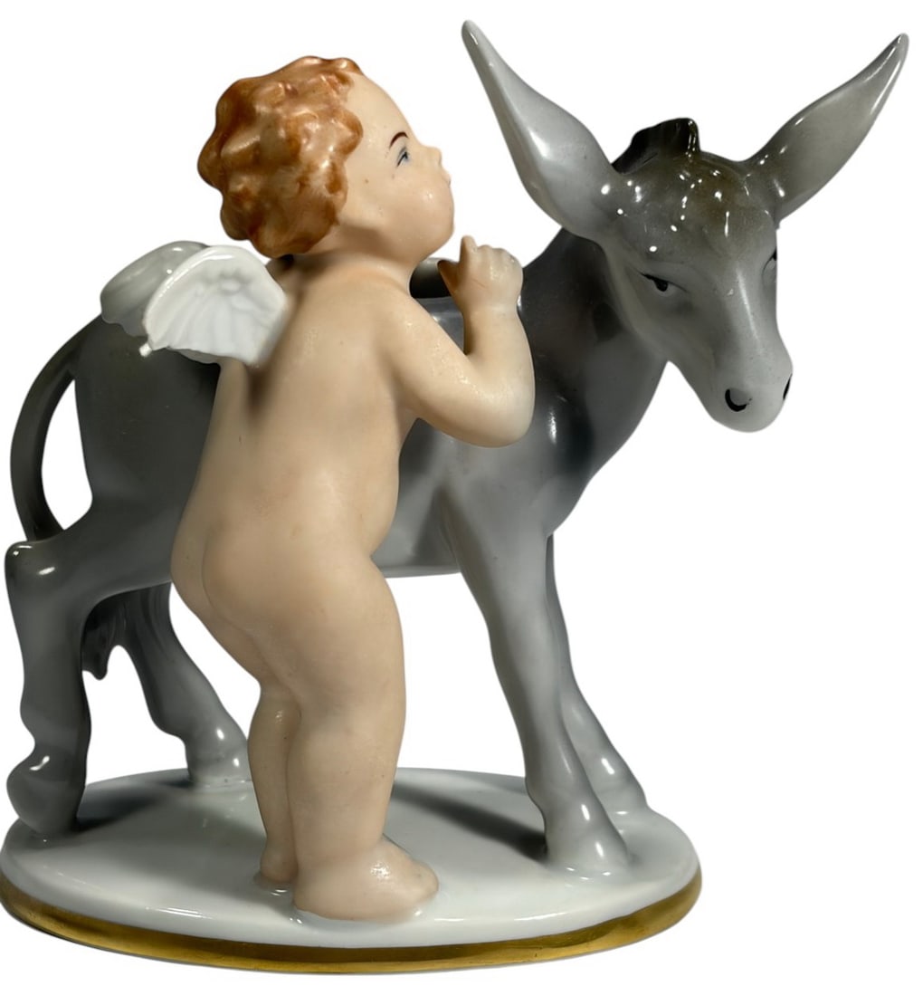 Gerold & Co Tettau Putti w/ Donkey Porcelain Fig: Gerold and Co Tettau Bavaria porcelain figurine of a winged putti with gray donkey. Nude cherub with white wings and softly painted features leaning against the donkey, on oval white base with gilt tr