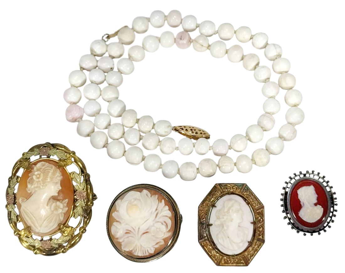 Vintage Cameo Brooches & Angel Skin Coral Necklace: Lot of four vintage and antique cameo brooches paired with a stranded angel-skin coral beaded necklace. The coral beaded necklace measures approximately 18.25 inches long. The largest cameo pendant