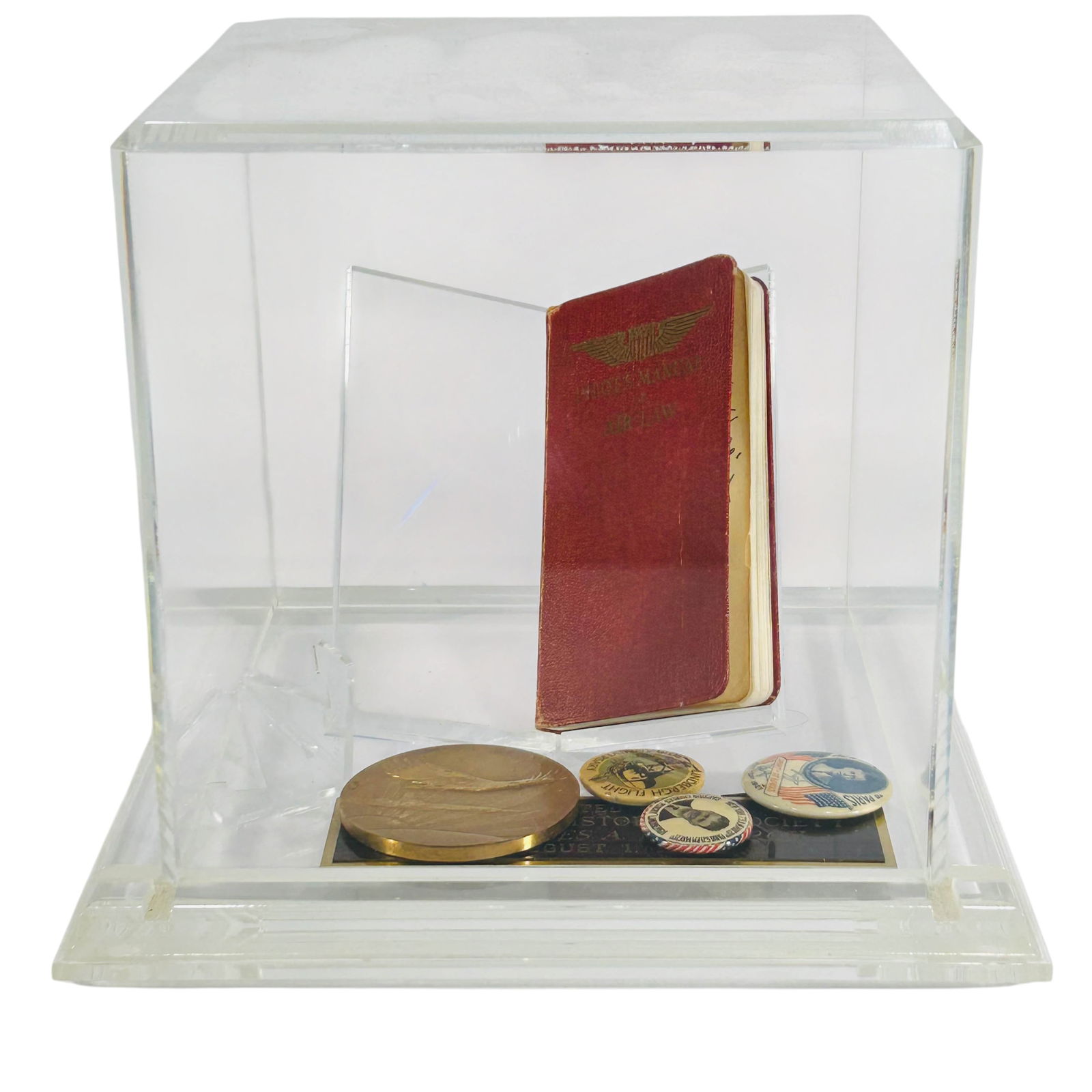Lindbergh Signed Book Pins Medal Aviation Display: Grouping includes a 1929 Pilots Manual of Air Law signed and inscribed by Charles A. Lindbergh to the Minnesota Historical Society, dated August 1, 1933. Set in a clear lucite acrylic case with presen