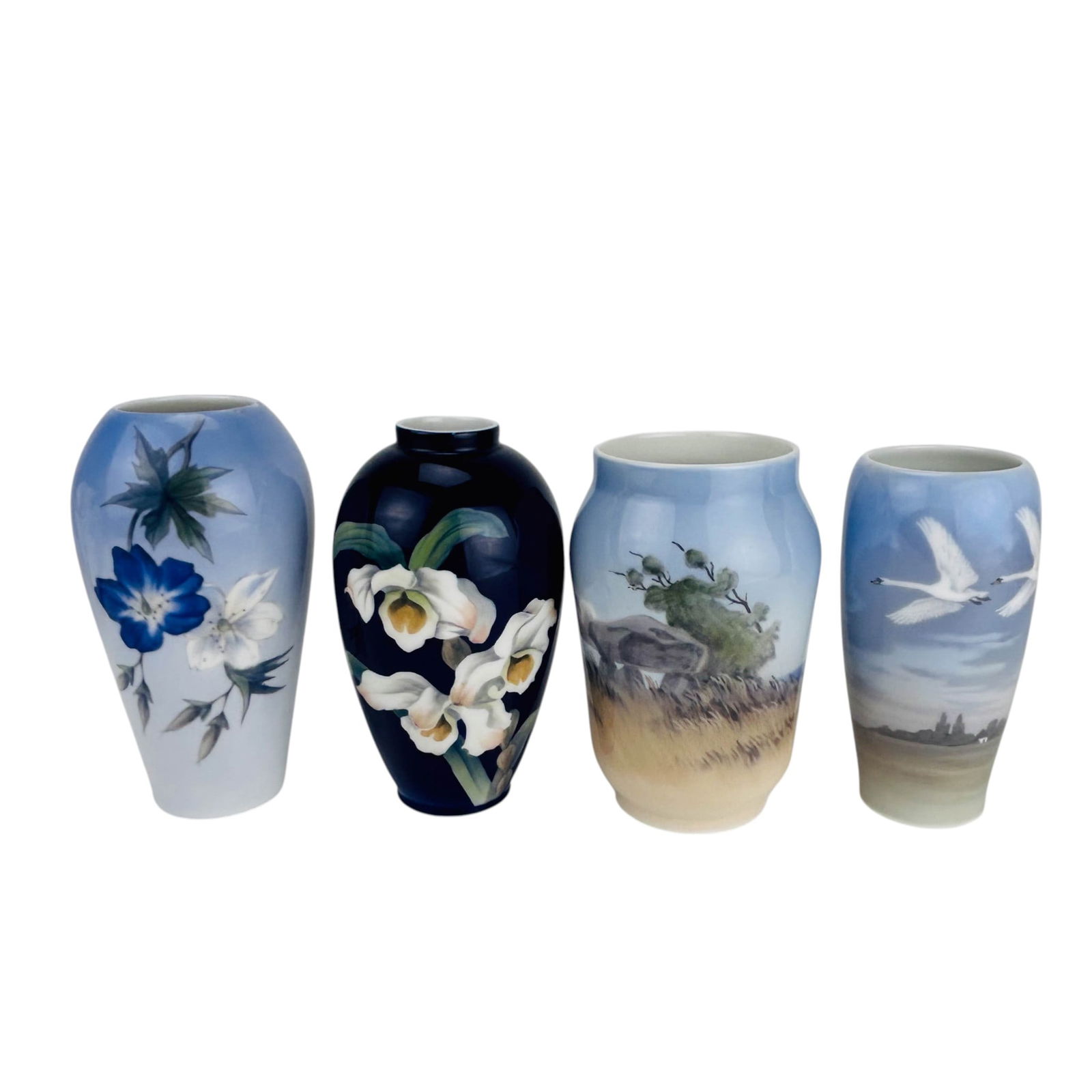 Royal Copenhagen Floral Swan Landscape Vase LOT: Royal Copenhagen Denmark porcelain vase four piece grouping. Motifs include white blossoms against a deep cobalt ground, a waterscape featuring two swans in flight, a pastoral landscape with rock form