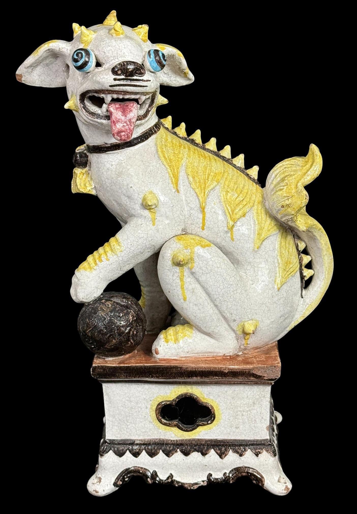 Large Chinese Glazed Ceramic Foo Dog Sculpture: A large, decorative Chinese-style ceramic Foo Dog figural sculpture seated on a raised platform footed base. The Foo Dog features an expressive face with its mouth open, tongue out with on paw resting