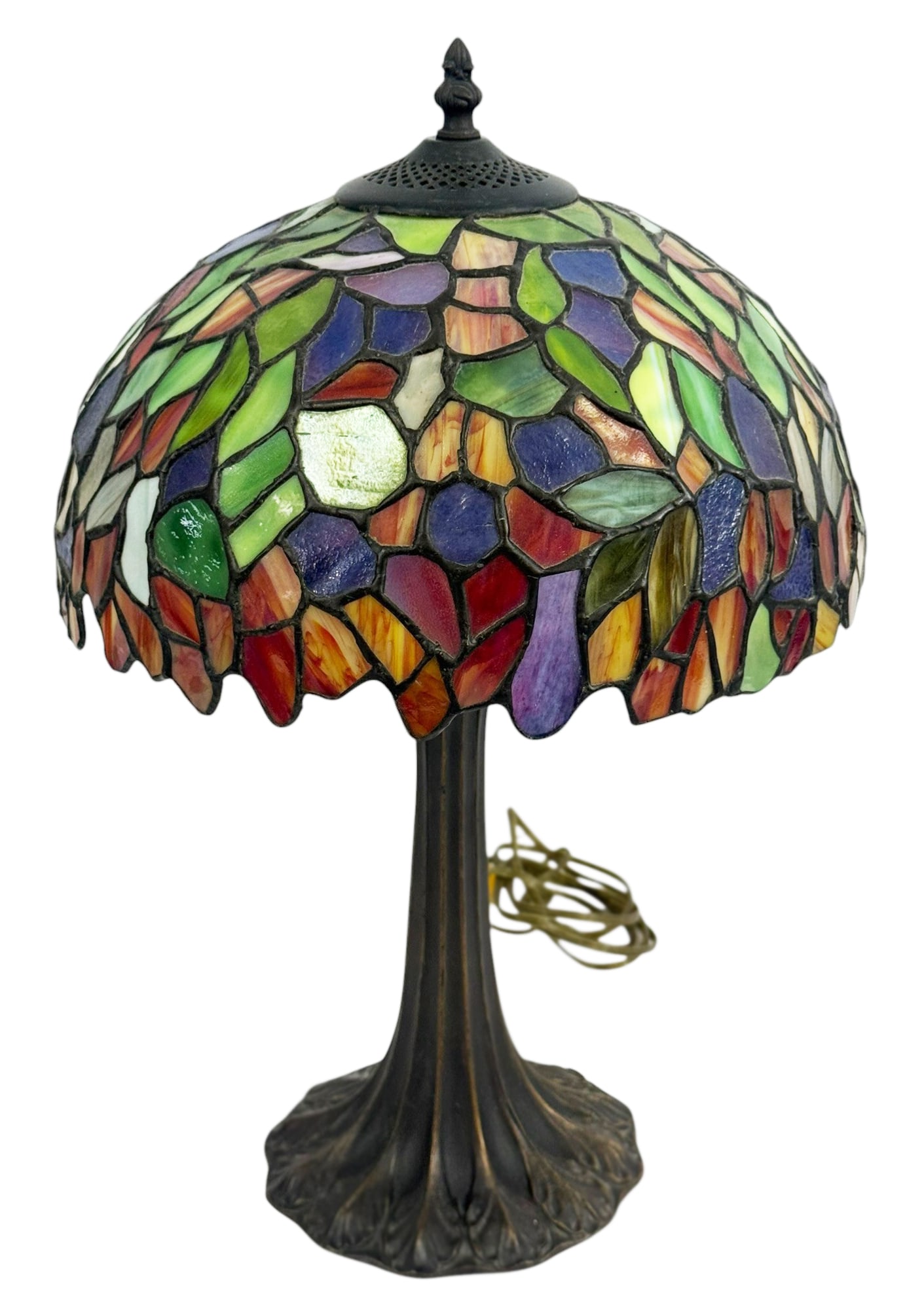 Tiffany Style Stained Glass Table Lamp 19" H: Tiffany style table lamp featuring a multicolor stained glass shade with leaf form mosaic pattern. The shade is mounted on a bronze tone metal base with a flared organic form.Dimensions: 19.25 X 12 X