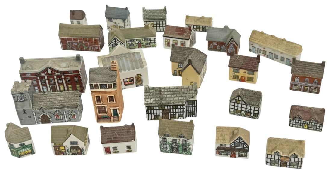 Wade English HP Miniature Village Houses 25pc LOT: Collection of twenty five Wade English miniature porcelain village buildings. The group includes assorted cottages, houses, shops, and a church rendered in traditional English village architectural st