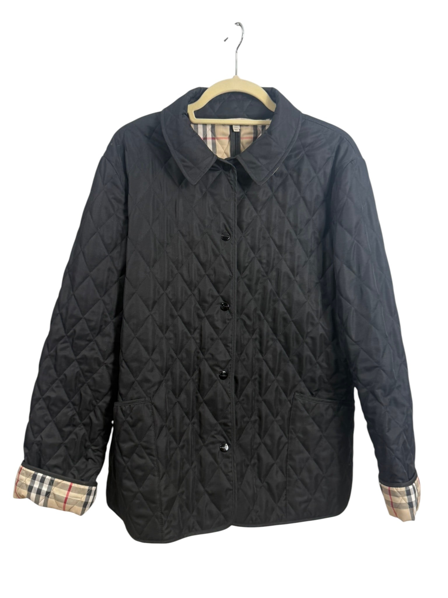 Burberry London Black Nova Check Quilted Jacket: Burberry London, black quilted jacket with a multi-button snap front closure and signature nova check interior lining. Features a pointed collar and front patch pockets. Labeled Burberry London and ma