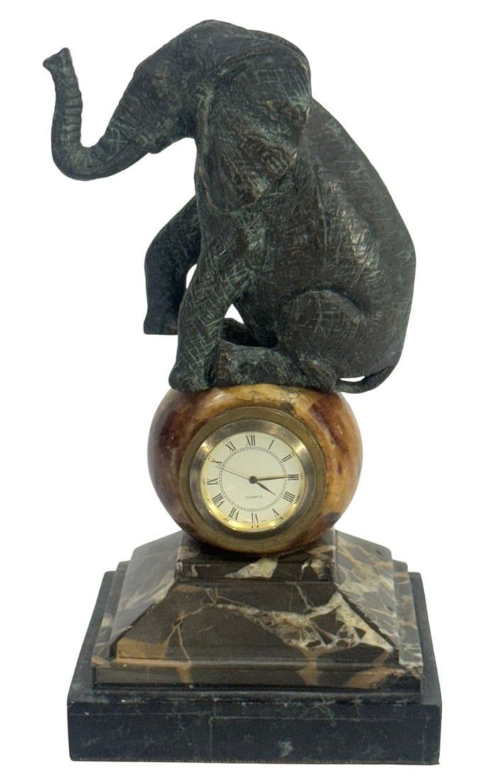 Maitland Smith Elephant Figural Marble Desk Clock: Maitland Smith figural desk clock featuring a verdigris finished cast brass elephant seated above a stone sphere with inset quartz clock. The piece is mounted on a stepped marble base and retains the