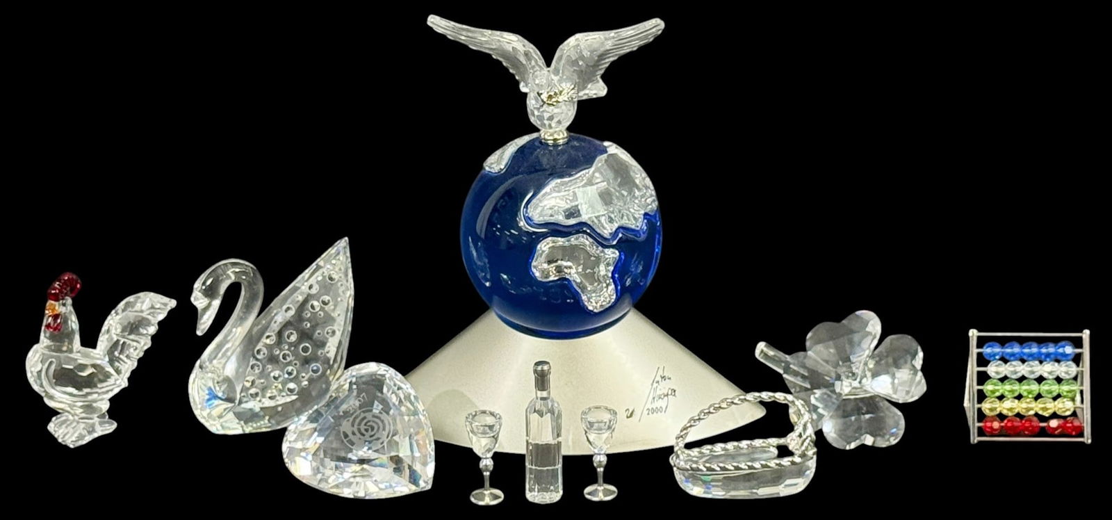 Swarovski Crystal Figurines & Trinkets 11pc LOT: Swarovski, a group of eleven crystal figurines and decorative objects. The lot includes a dolphin figure, Harlequin SCS figure with box, globe with dove dated 2000, swan, rooster, flower, small goblet