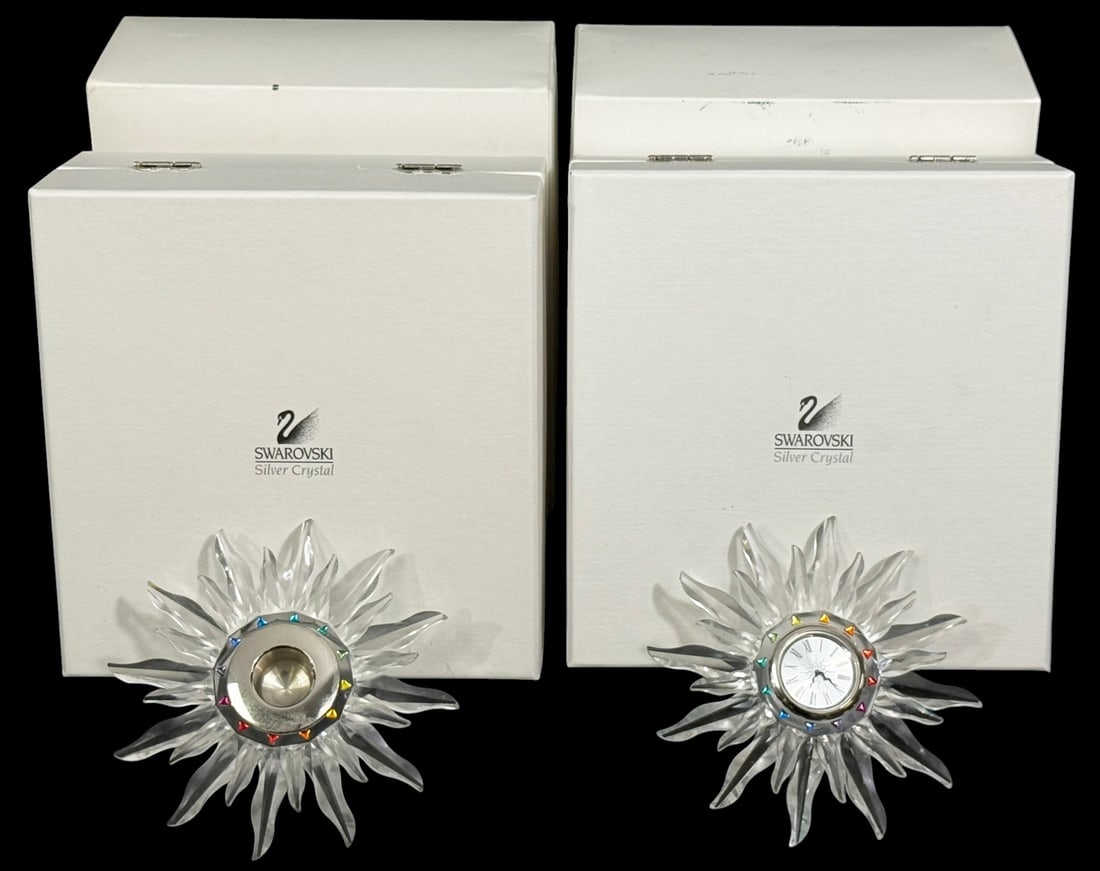 Swarovski Crystal Solar & Sun Clock w/ Box 2pc LOT: Swarovski crystal solar and sun form desk clocks with faceted rays and colored crystal accents around the dial. Each clock features a Roman numeral face set within a radiating crystal design. Both ret