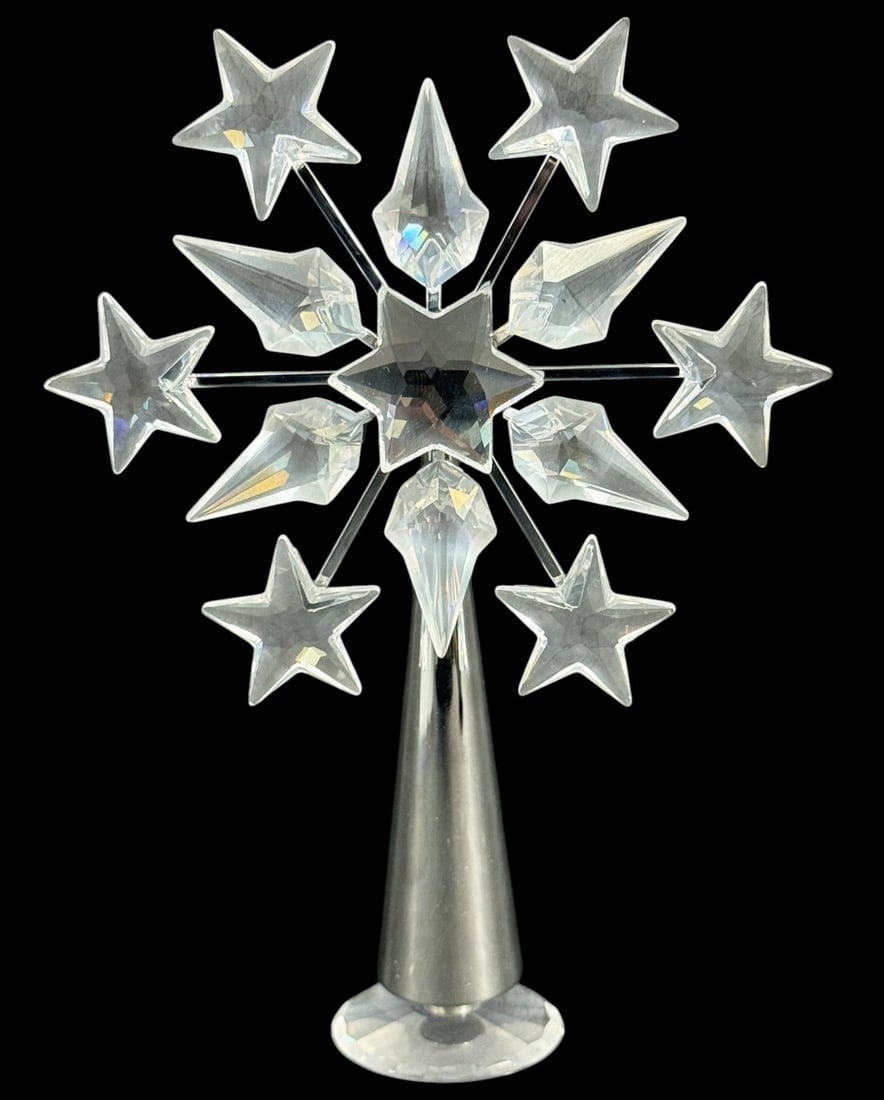 Swarovski L/E Crystal Star Tree Topper Ornament: Swarovski, a crystal star tree topper ornament with radiating star and icicle form points mounted on a metal stand. The design features clear faceted crystal elements arranged around a central star.