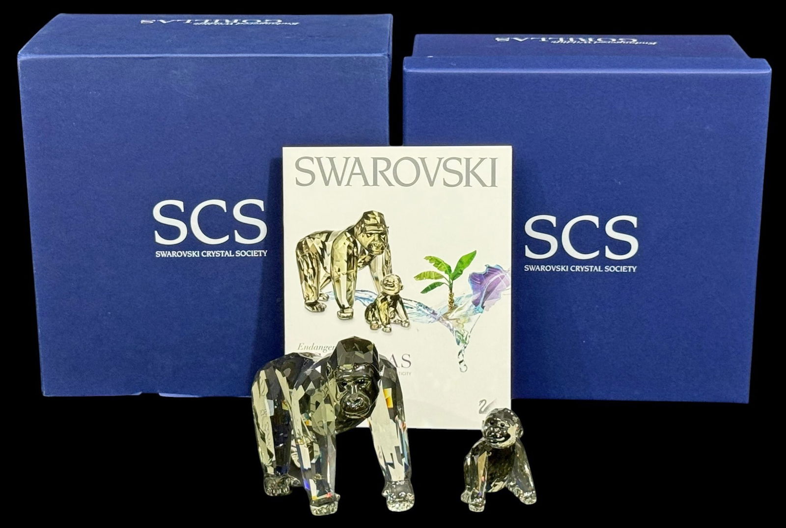 Swarovski Crystal Annual Edition 2009 Gorillas Fig: Swarovski crystal Annual Edition 2009 gorilla figurines, including a large gorilla and a smaller baby. Each figure is formed in faceted clear crystal with light tinting and detailed features. The