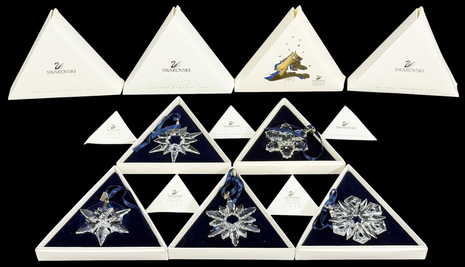 Swarovski Crystal Annual Christmas Ornaments 5pcs: Lot of five Swarovski crystal annual Christmas star ornaments. The group includes multiple late-1990s and 2000 designs, each with faceted crystal star forms and blue ribbon hangers. All ornaments are
