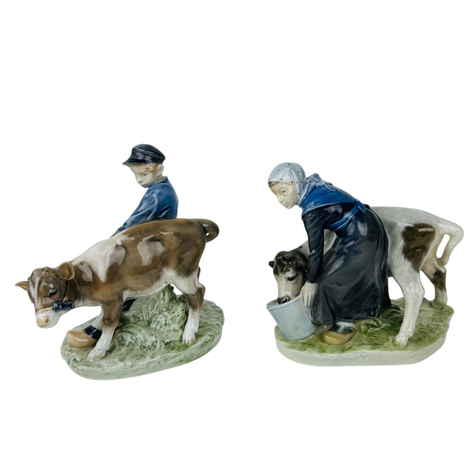 Royal Copenhagen Boy & Girl w/ Calf Figurine LOT: Royal Copenhagen Denmark lot of two curio cabinet porcelain pastoral farm scene figurines. Includes Boy with Calf # 772 featuring a young boy guiding a calf across a grassy ground. The other titled Gi