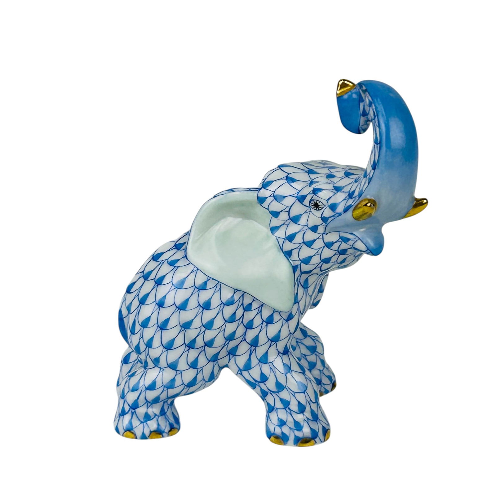 Herend Blue Fishnet Elephant Trunk Up Figurine: Herend Hungarian porcelain Elephant figurine rendered in the signature Blue Fishnet scale pattern over a white ground. The standing animal with trunk raised upwards displays hand painted detailing wit