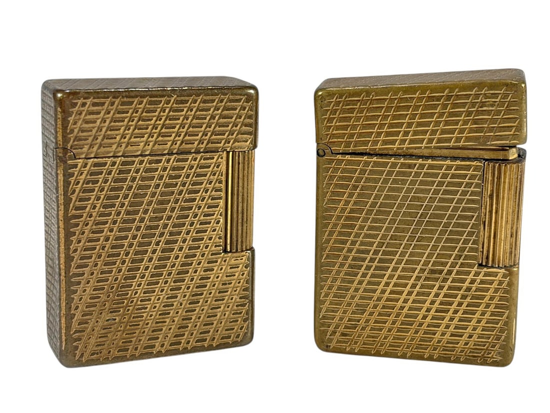 St Dupont Paris Ligne 1 Gold Plated Lighters 2pcs: Pair of S.T. Dupont Ligne 1 lighters in gold plated finish, classic rectangular form with engraved crosshatch pattern, made in France, includes two matching examples with visible serial markings. Each