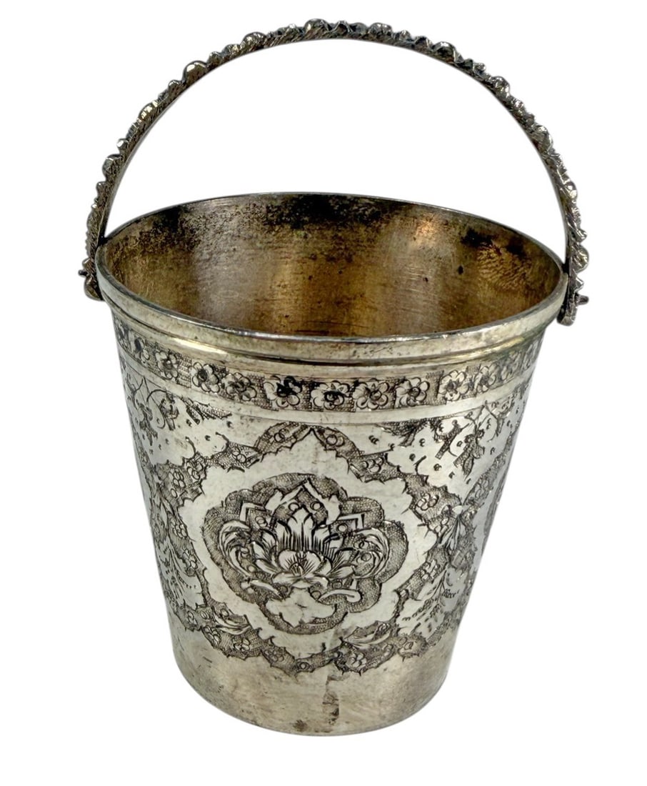 Antique Persian Silver Miniature Ornate Ice Bucket: Persian silver miniature ice bucket with tapering cylindrical form and swing handle, engraved with dense floral ghalam zani decoration. Marked with Isfahan maker and retailer's marks, including Mahmud