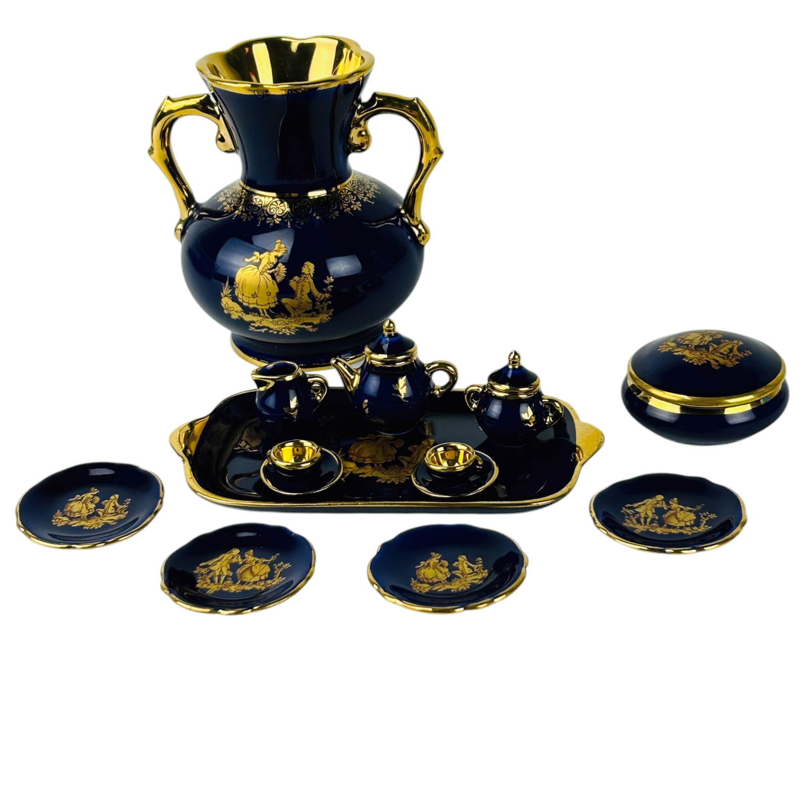 Limoges France Porcelain Vase & Mini Tea Service: Grouping of Limoges French porcelain collectibles in cobalt ground with gilt figural decoration. Lot includes a two handle vase, covered domed pill box, a mini rectangular tray with handles, four mini