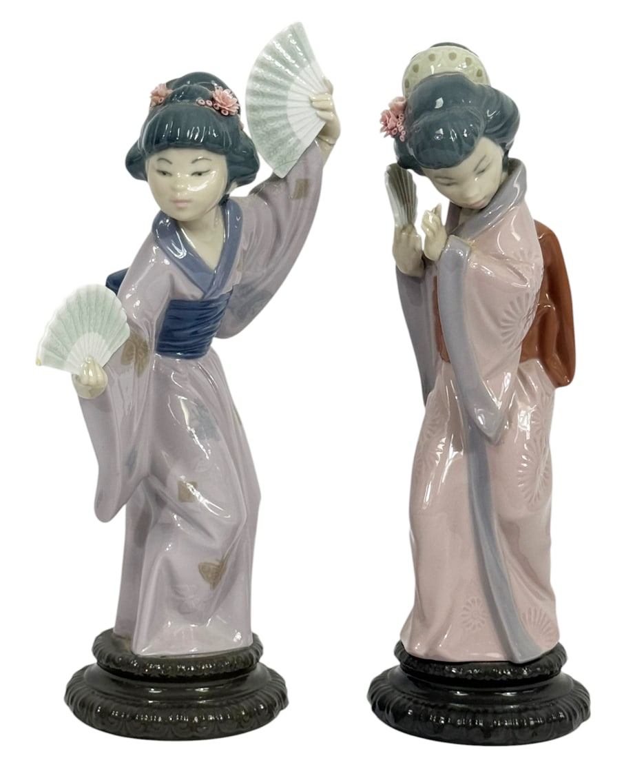 Lladro Madame Butterfly & Timid Japanese Figurines: Lot of two Lladro Spanish porcelain figurines titled "Madame Butterfly" and "Timid Japanese Woman". Both pieces retain the blue Lladro stamp mark underneath their bases. The largest measures approxima