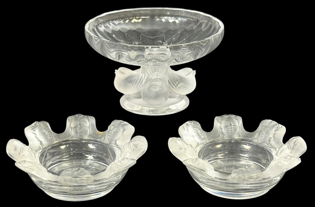 Lalique Nogent Compote & Saint Nicholas Ashtrays: Three-piece Lalique French crystal decorative items. To include a "Nogent" footed compote bowl and a pair of "Saint Nicholas" ashtrays. Each piece is signed "Lalique France" in script underneath their