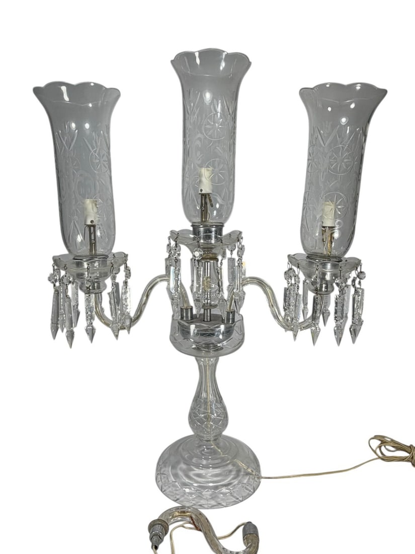 Baccarat Style Crystal Three Lights Girandole Lamp: Baccarat style crystal three light girandole candelabra lamp, central standard with scrolling arms and etched hurricane shades, hung with prisms and spear drops, cut crystal stem and base, electrified