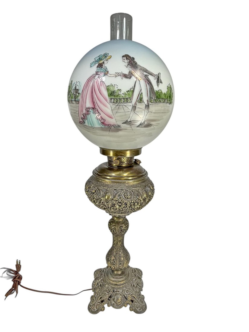 Bradley & Hubbard Style Metal & Glass Oil Lamp: Bradley and Hubbard style metal and glass oil lamp featuring an ornate cast base with scrolling floral relief in antique brass tone, fitted with clear glass chimney and hand painted opaline glass font