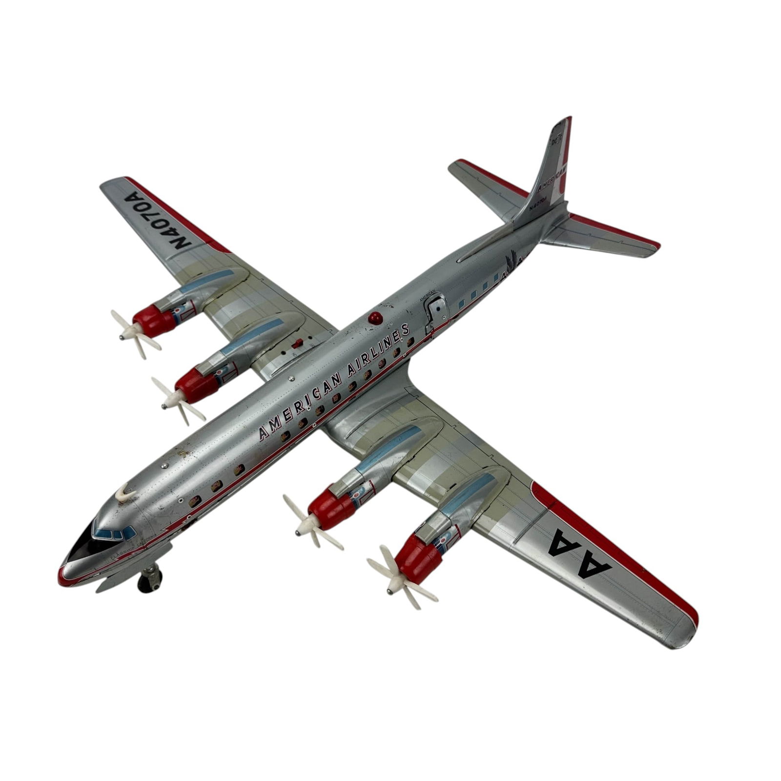 American Airlines DC-7C Tin Toy Model Airplane: Tin lithograph airplane model marked American Airlines and DC-7C with registration N4070A. Four engine propeller design with landing gear and window graphics showing passengers. Underside marked Made