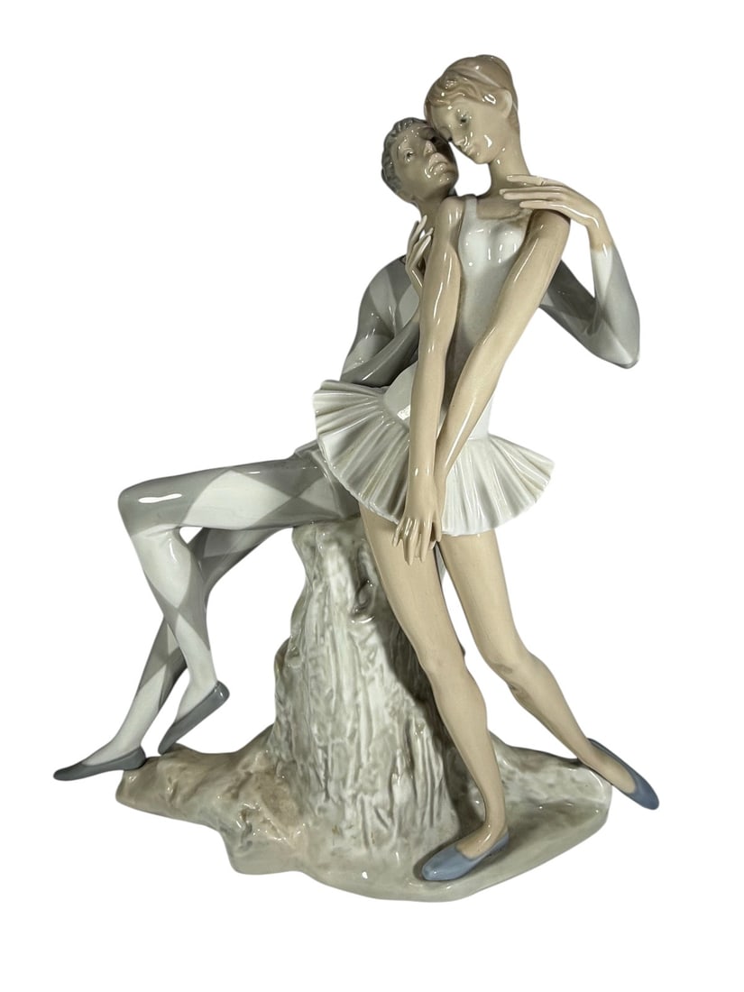 Lladro Idyl Harlequin & Ballerina Porcelain Fig: Lladro Spain, porcelain figural group of Harlequin and ballerina in seated pose, soft pastel tones with detailed costumes and finishes. Marked to its base. Dimensions: 13.75 X 11.5 X 4.75 in. Conditio