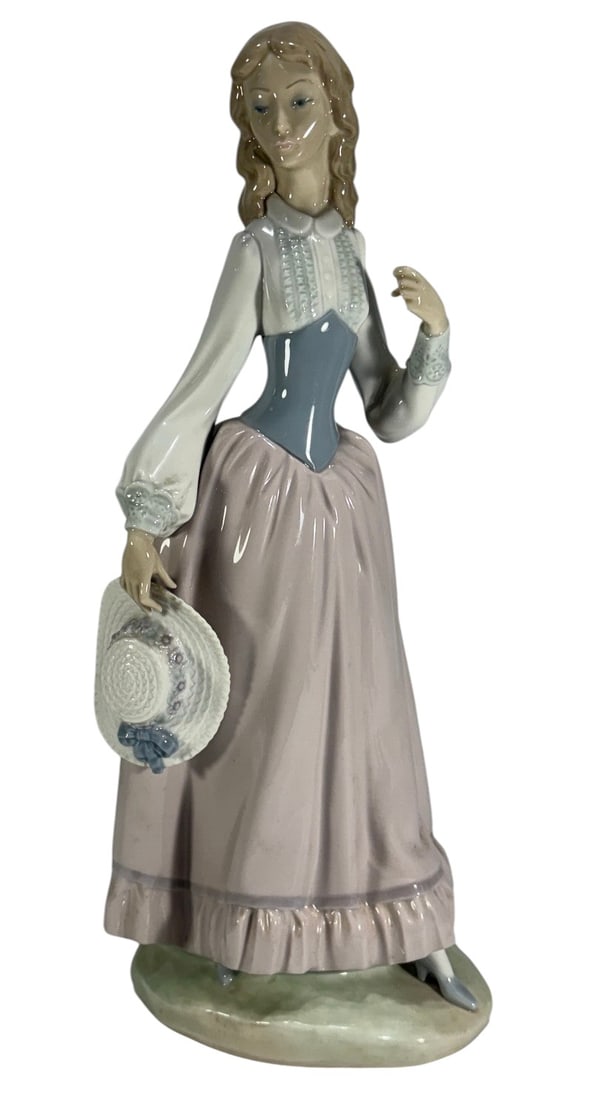 Lladro Spain Eloise by Vicente Martinez Figurine: Lladro Spain, Eloise porcelain figurine by Vicente Martinez, retired 1981, depicting a woman in period dress holding a bonnet, soft pastel tones with detailed finish, marked to its base. Dimensions: 1